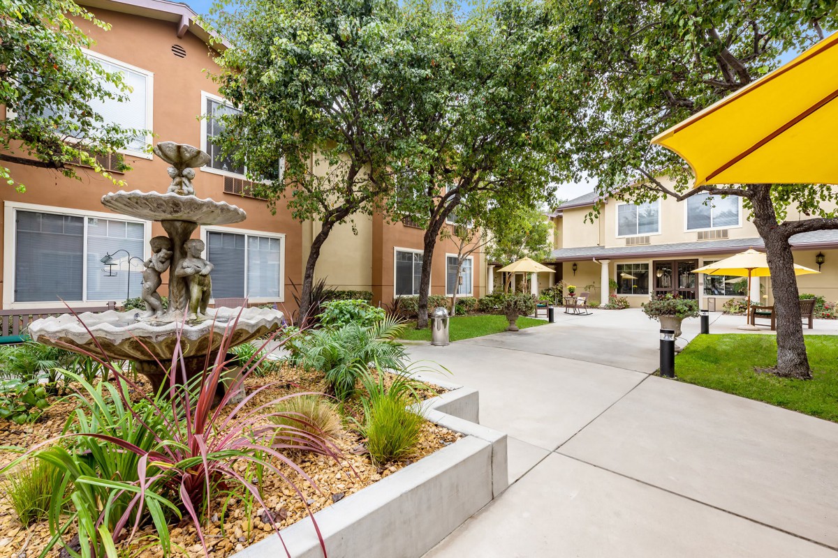 A tranquil courtyard in an apartment complex with a fountain and lush landscaping.