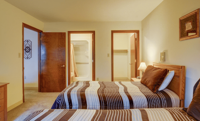 A cozy bedroom with a striped bedspread and warm lighting.