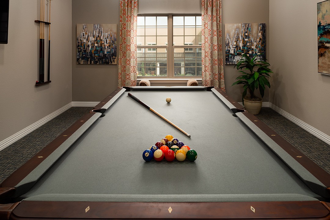 A well-lit game room featuring a neatly arranged pool table ready for play.