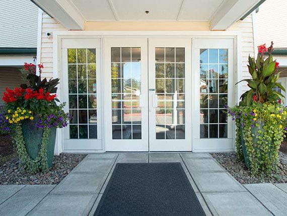 A welcoming entrance with glass double doors and decorative potted plants.