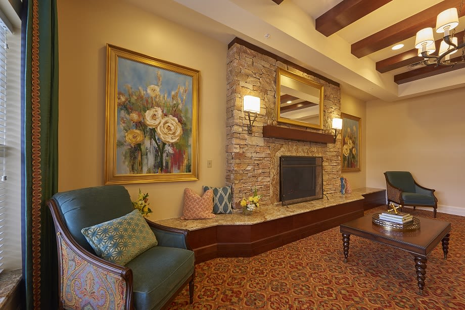 A cozy living room with a stone fireplace, elegant artwork, and comfortable seating.