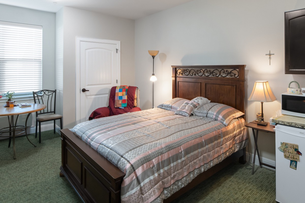 A cozy bedroom with a wooden bed, striped bedding, and a floor lamp beside it.