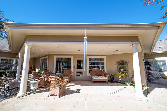 A sunny patio with wicker furniture and decorative plants under a clear blue sky.