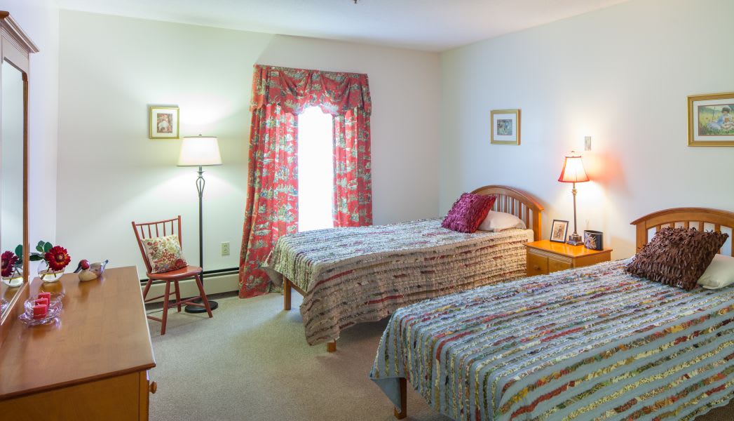 A cozy bedroom with twin beds, colorful curtains, and a warm ambiance.