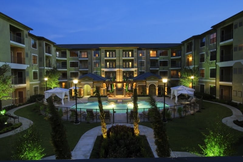 A beautifully lit resort with a centrally located pool at night.