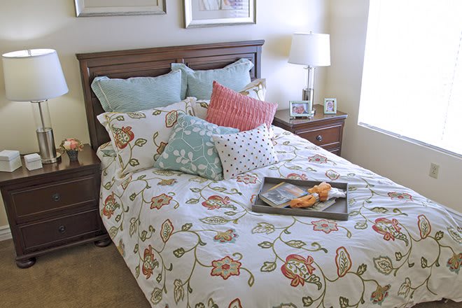 A cozy bedroom with a floral patterned bedspread and an assortment of decorative pillows. A tray with breakfast sits invitingly on the bed.