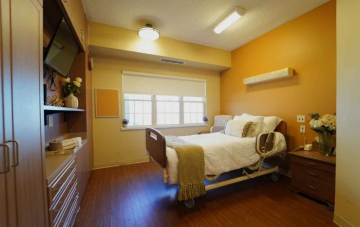 A well-lit hospital room with a single patient bed and modern amenities.