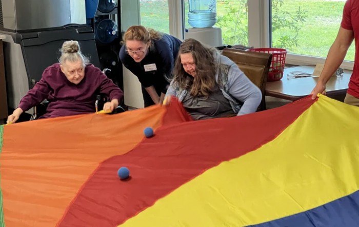 Seniors engaged in a colorful parachute activity indoors.