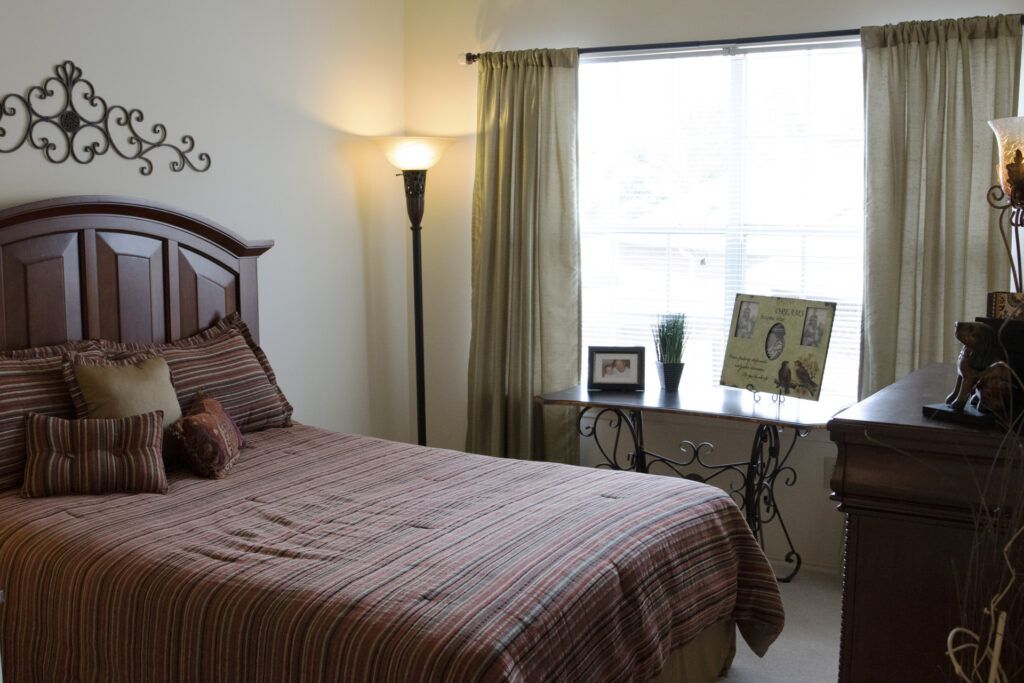 A cozy bedroom with a bed, floor lamp, and window letting in natural light.