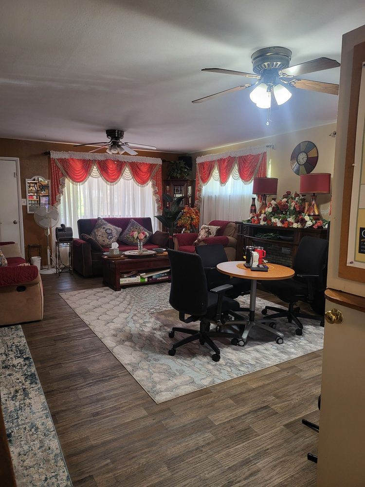A cozy living room featuring a mix of seating and dining areas, with red curtains and various decorations.