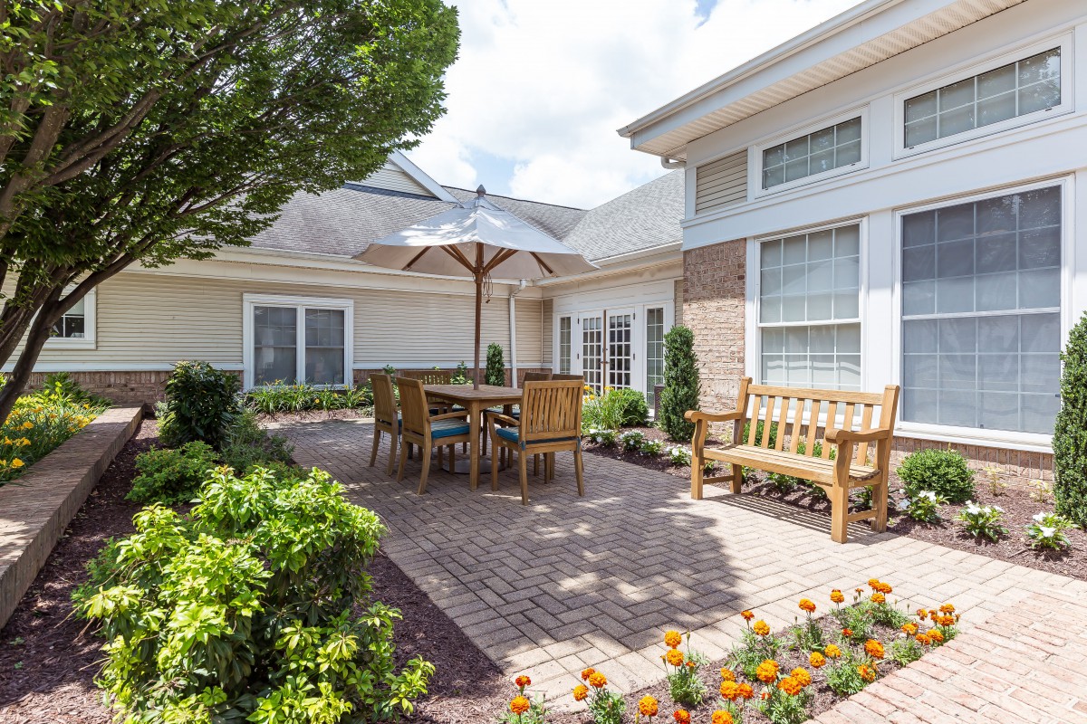 A cozy patio area with wooden furniture and a garden setting.