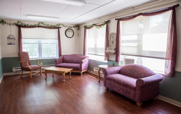 A cozy living room with purple sofas and wooden tables.