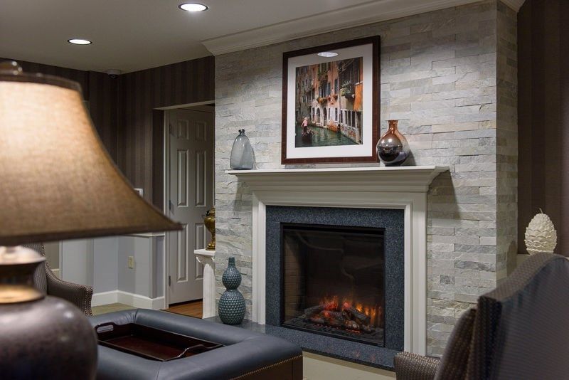 A cozy living room featuring a modern fireplace, decorated with artwork and vases.