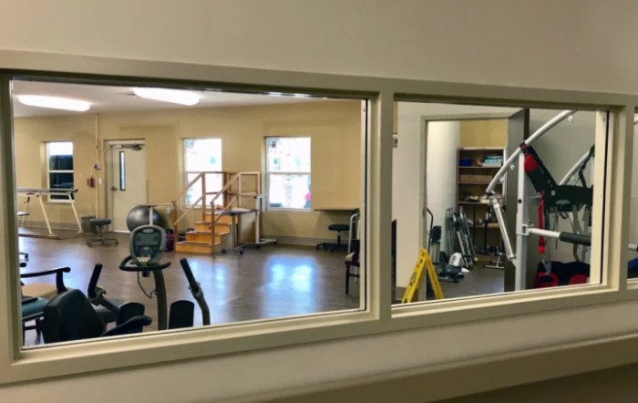 A view of a gym from across a window, showcasing various exercise equipment.