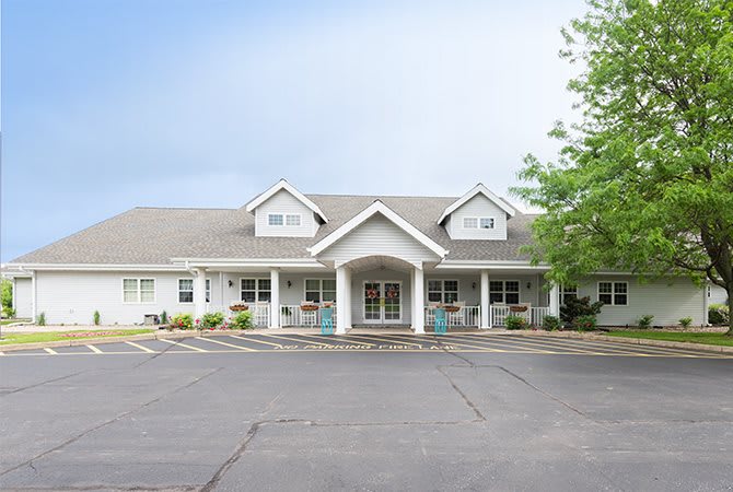 A white residential-style building with symmetrical architecture and a paved parking area.