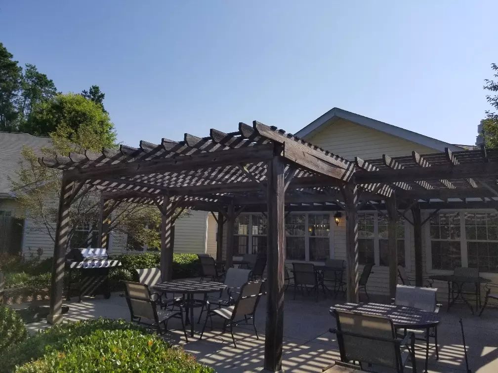 A sunny patio with a pergola and outdoor seating.