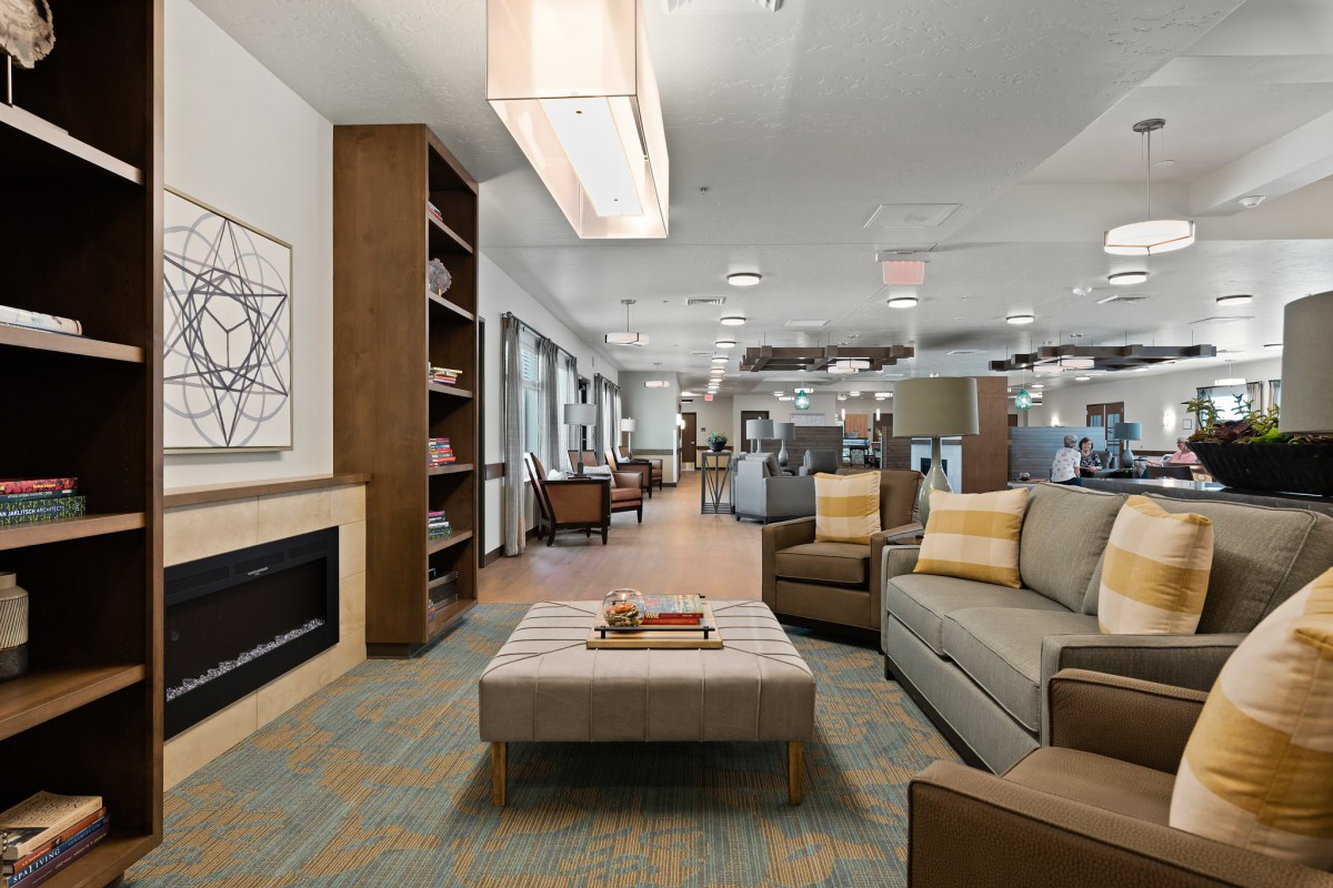 A modern lounge area with stylish furniture, a fireplace, and a bookshelf.