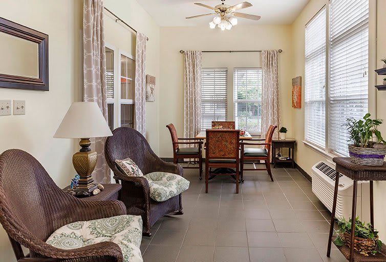A cozy living and dining area with wicker furniture and large windows.