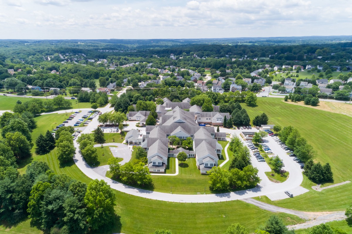 Aerial view of a building complex surrounded by greenery and roads.