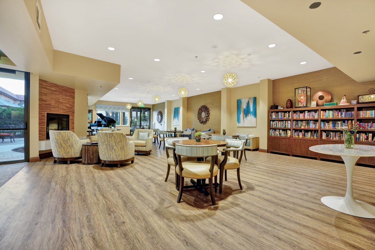 A cozy living room with comfortable seating, a bookshelf, and bright lighting.