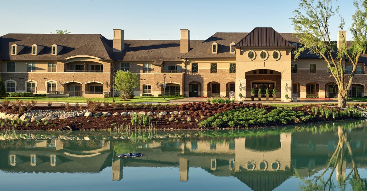 A luxurious building with elegant architecture reflected in a tranquil pond.