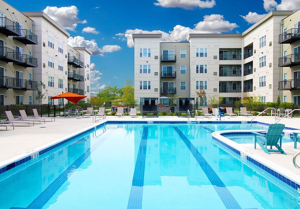 A modern apartment complex featuring a swimming pool on a sunny day.