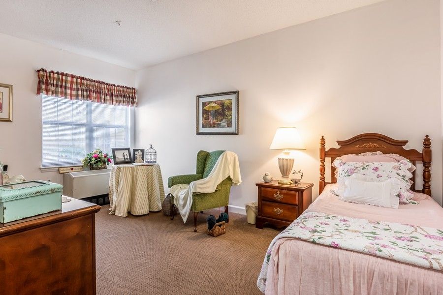 A cozy and well-furnished bedroom with a comfortable chair, bedside table, and soft lighting.