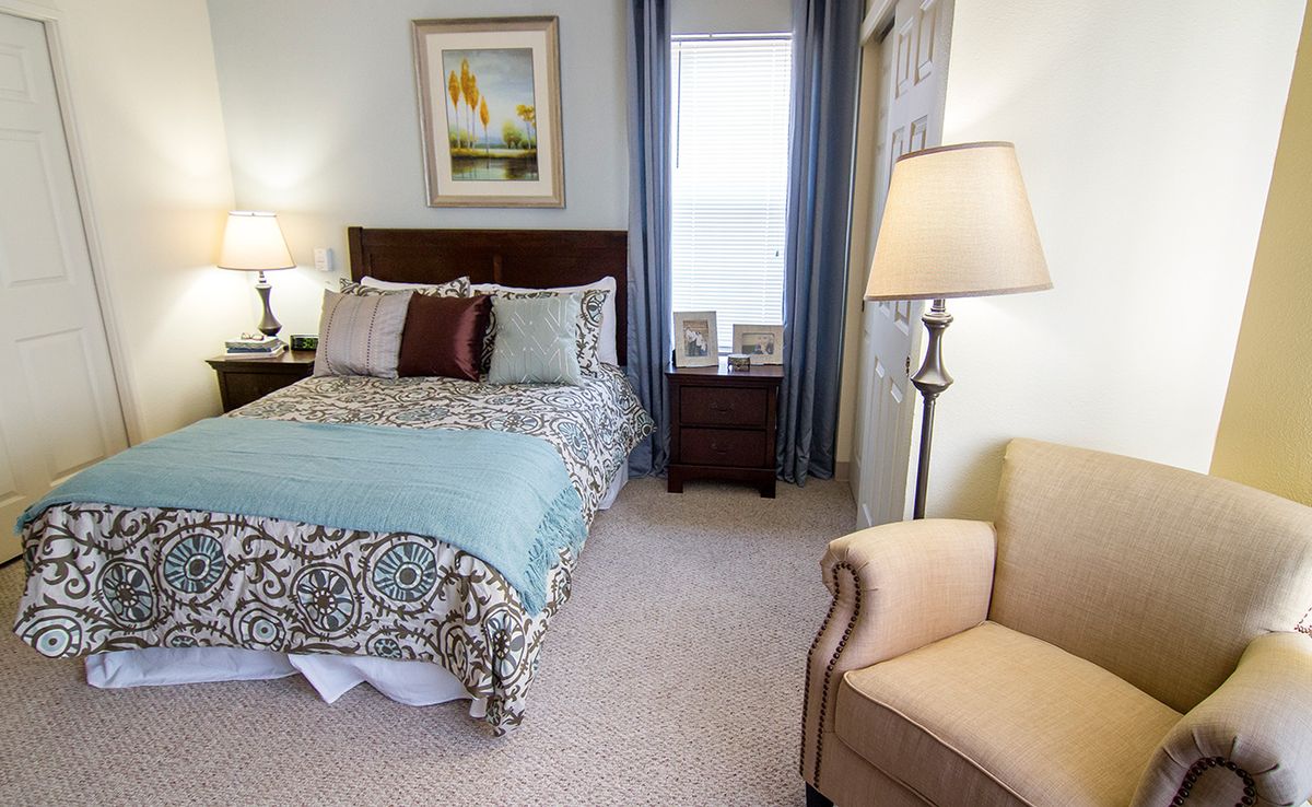 A cozy bedroom with a neatly made bed, a lamp, and comfortable furniture.