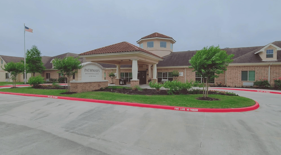 A building with an entrance surrounded by landscaping under an overcast sky.