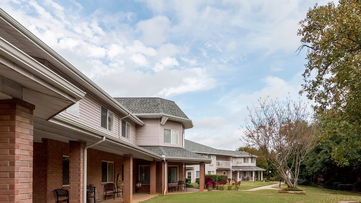 A row of suburban houses under a cloudy sky, with well-maintained lawns and trees.