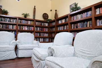A cozy reading area with white armchairs surrounded by bookshelves.