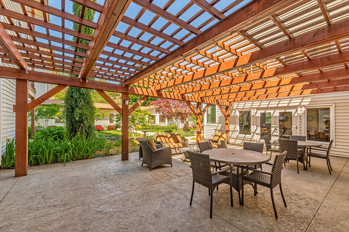 A sunny patio with a pergola and outdoor seating area in a garden setting.