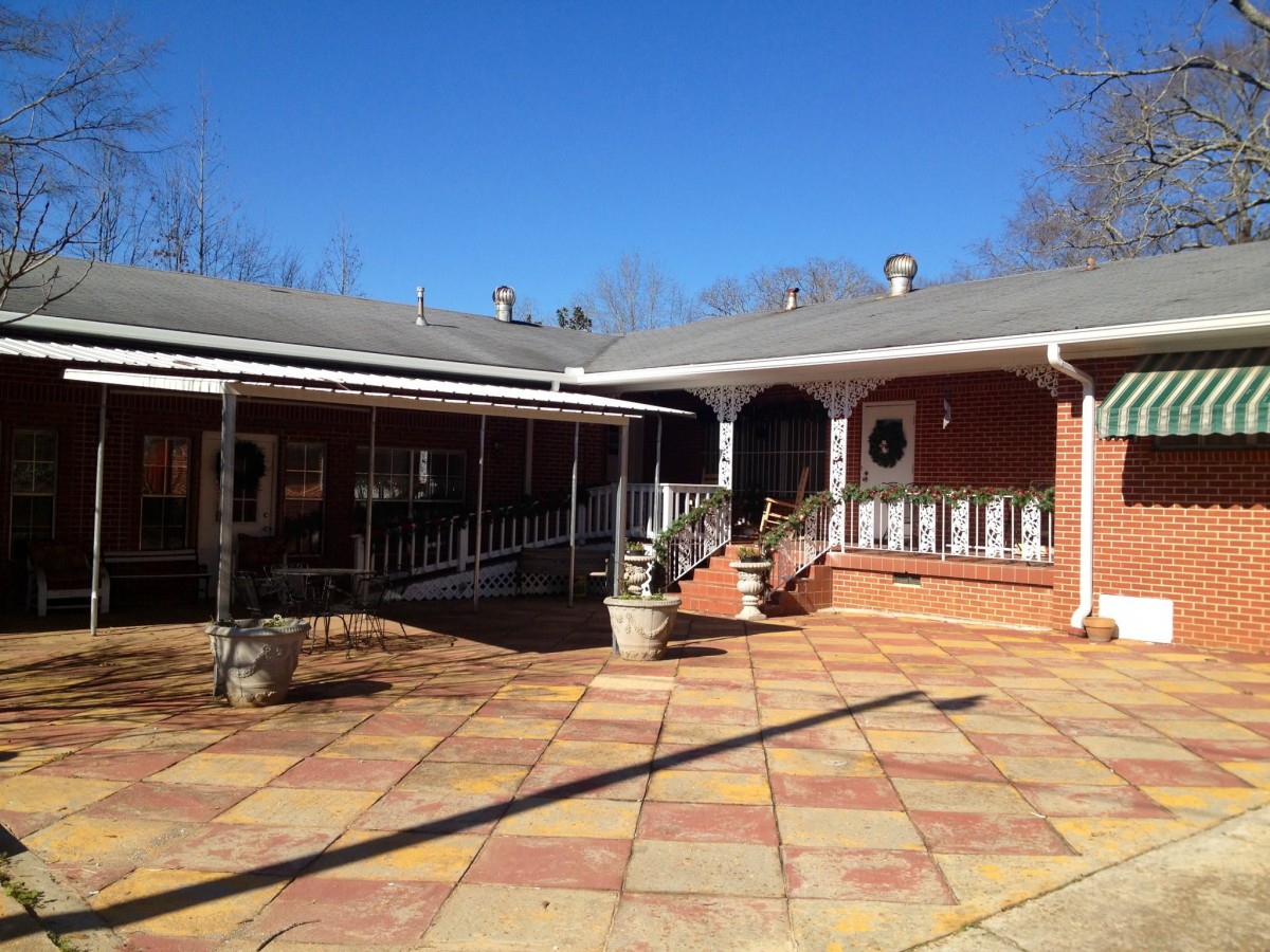A sunny courtyard with a brick building and a spacious patio area.