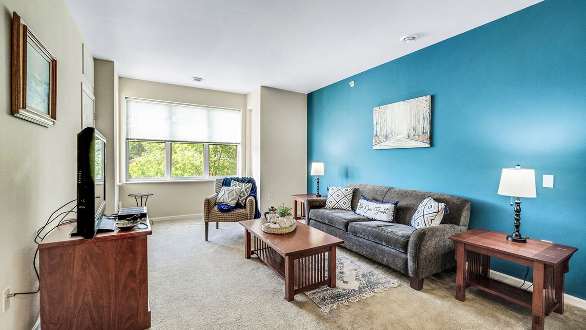 A cozy living room featuring a comfortable sofa and armchair, a wooden coffee table, and a bright blue accent wall.