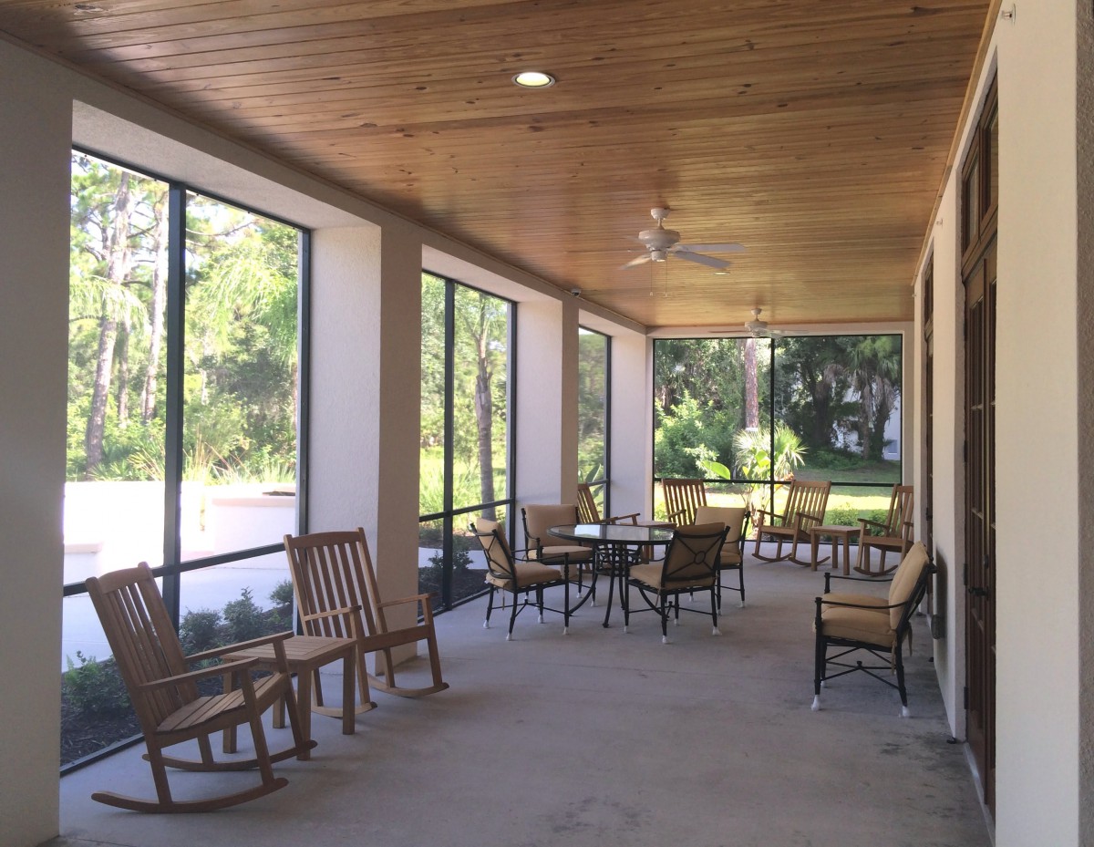 A spacious porch with rocking chairs and tables, perfect for relaxing on a sunny day.