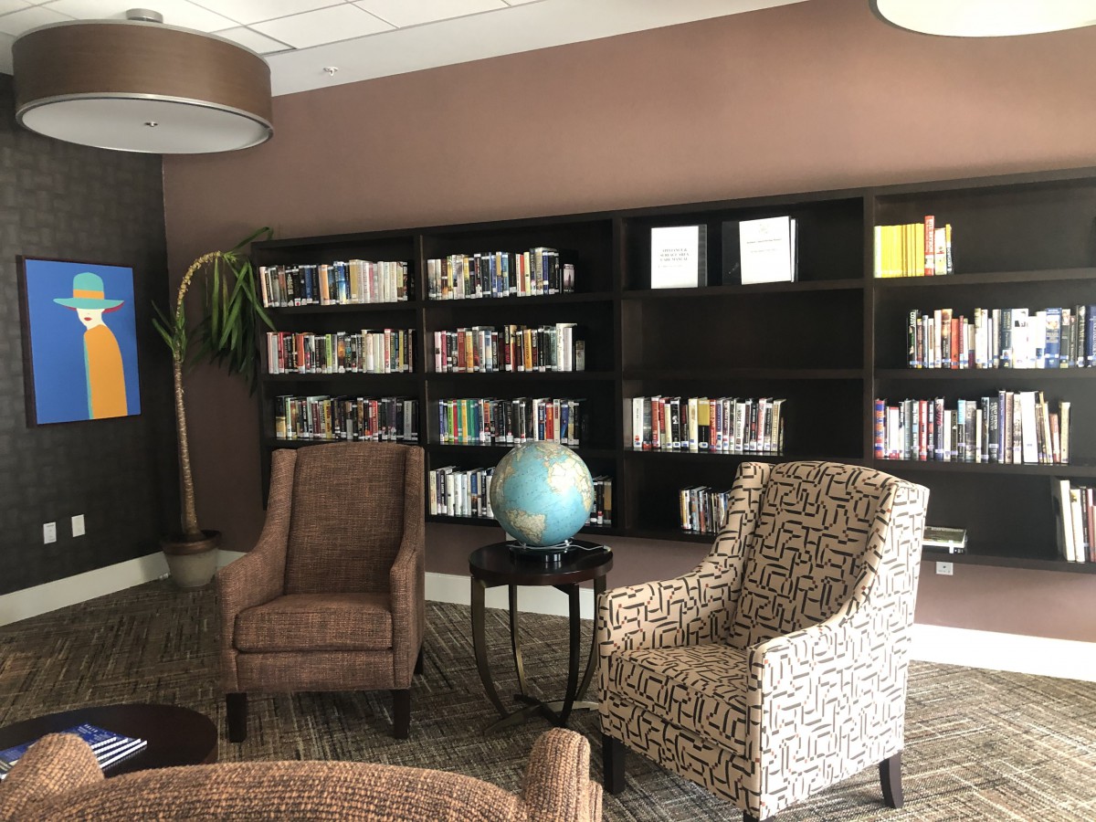 A cozy reading space with armchairs and a globe in front of a well-stocked bookshelf.
