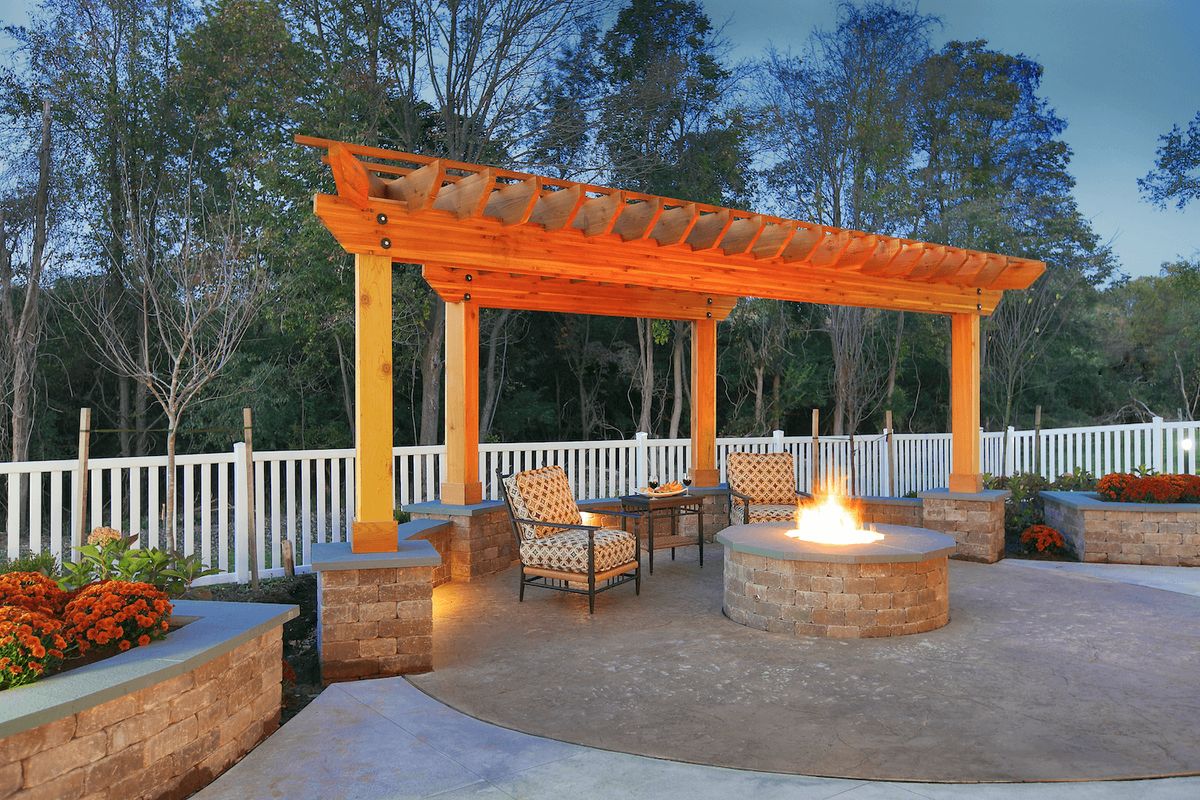 A cozy outdoor seating area with a pergola and fire pit, perfect for evening gatherings.