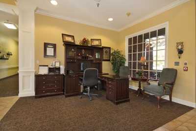 A well-furnished office space featuring a large desk with a computer, surrounded by bookshelves and cabinets.