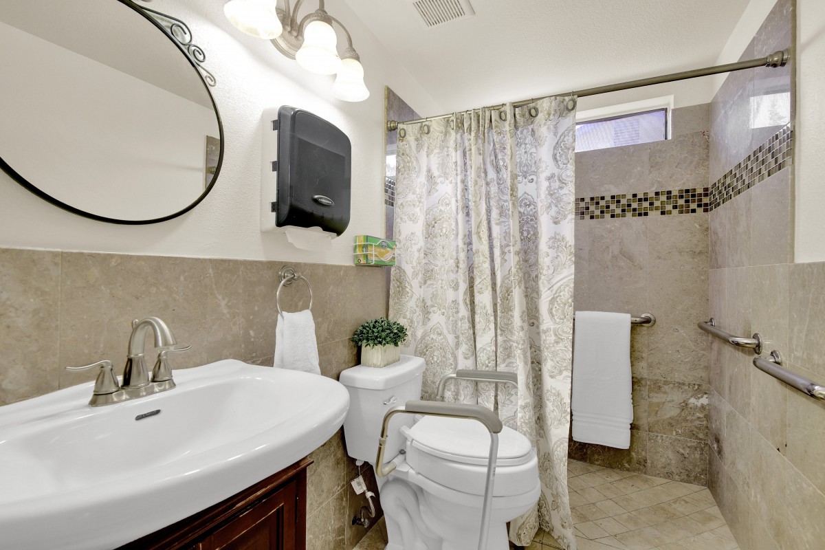 A clean and modern bathroom with a shower curtain and mirror above the sink.