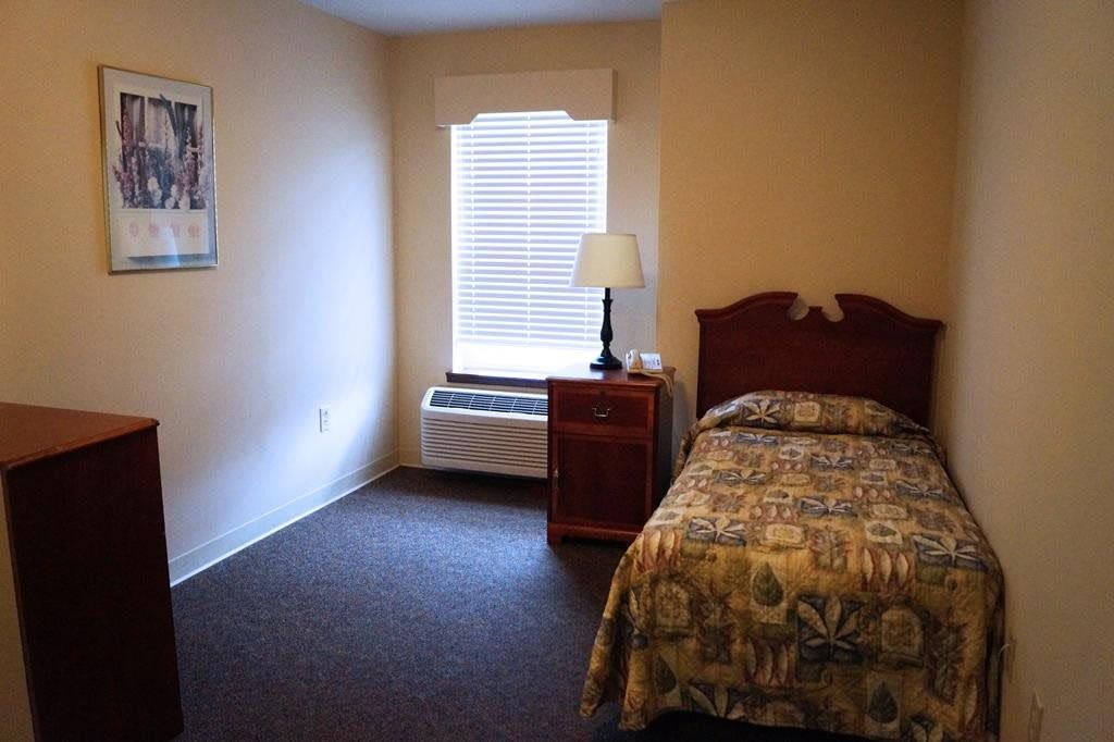 A small bedroom with a single bed, nightstand, and window.