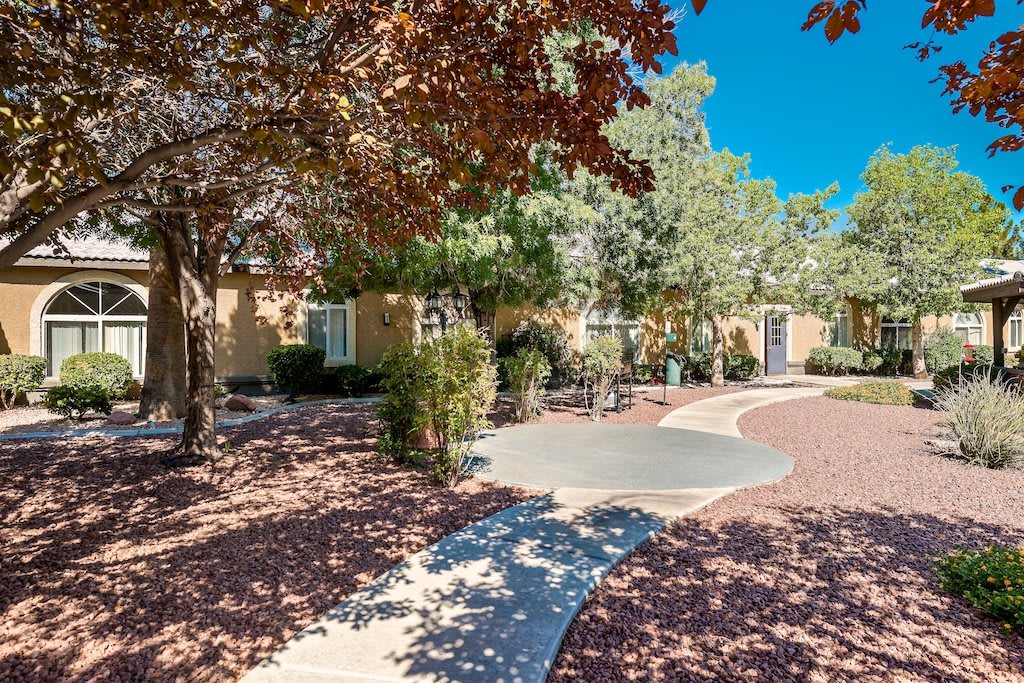 A charming residential house with a scenic driveway surrounded by trees and autumn foliage.