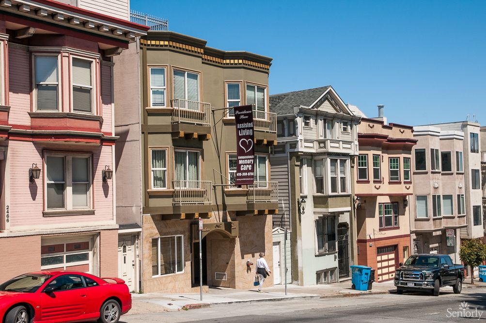 A street view of colorful residential buildings in a city with a clear blue sky.