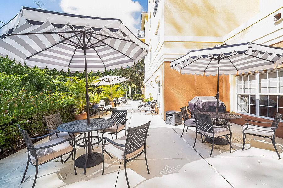 A sunny outdoor patio with tables, chairs, and large umbrellas.
