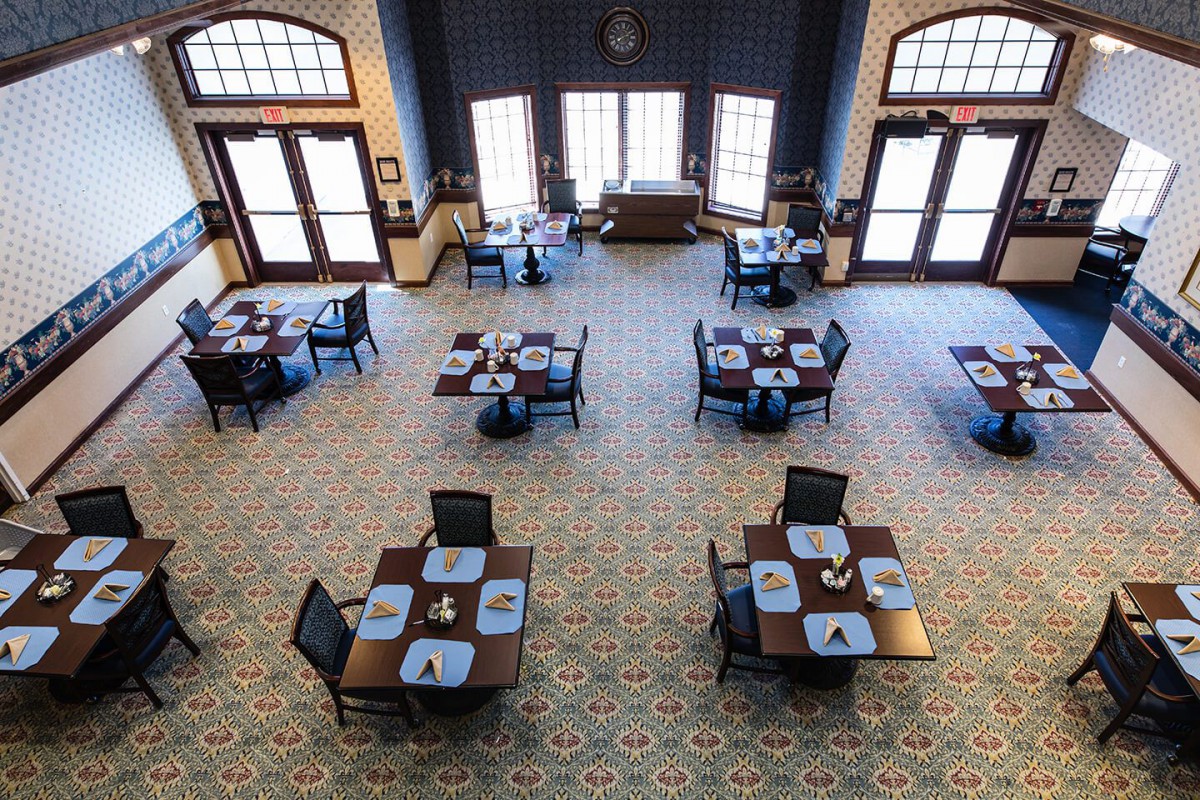 An empty dining area with neatly arranged tables and chairs, illuminated by natural light.