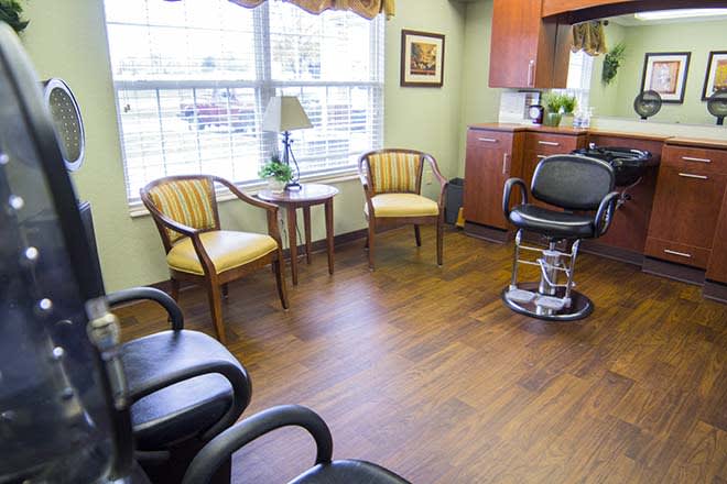 A salon waiting area with chairs and a barber chair by the window.