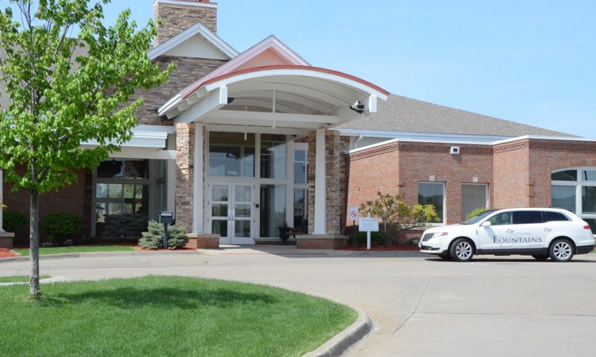 A building entrance with a driveway and a parked car.