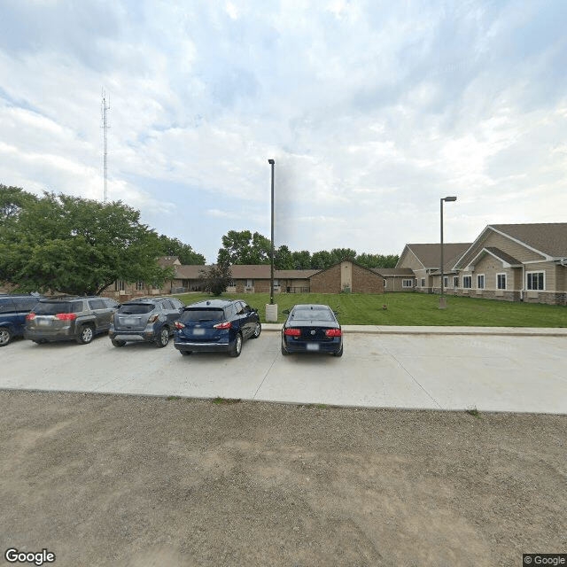 A parking lot with several cars and buildings under an overcast sky in a suburban area.