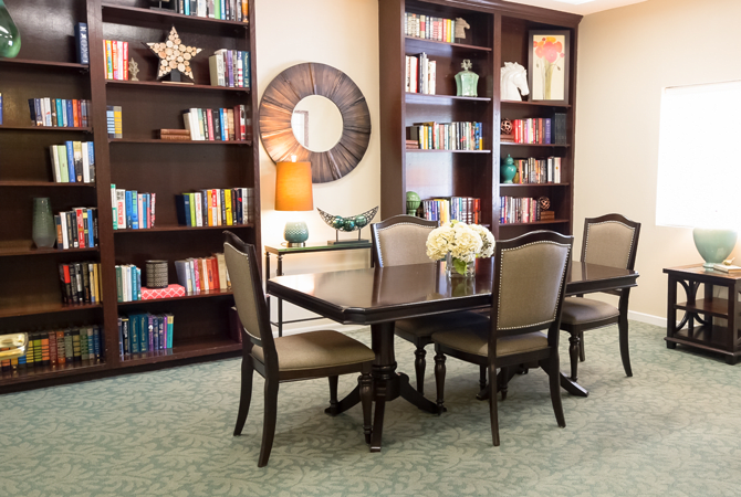 A cozy library setting with bookshelves, a table, and chairs.