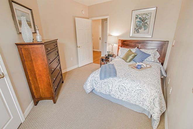 A cozy bedroom with a neatly made bed, wooden dresser, and soft lighting.