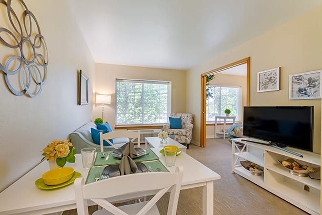A bright and cozy living room with an adjacent dining area, featuring modern decor and ample natural light.